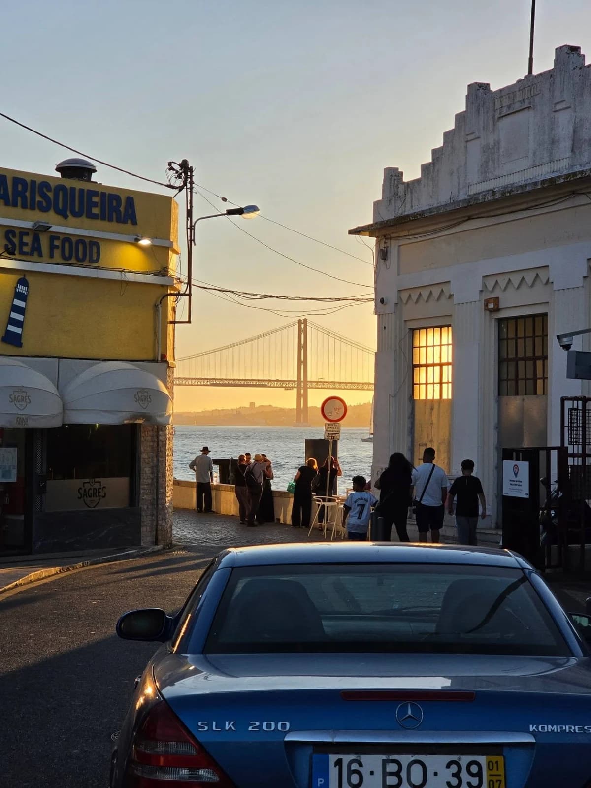 A street opening onto the water and a suspension bridge at sunset